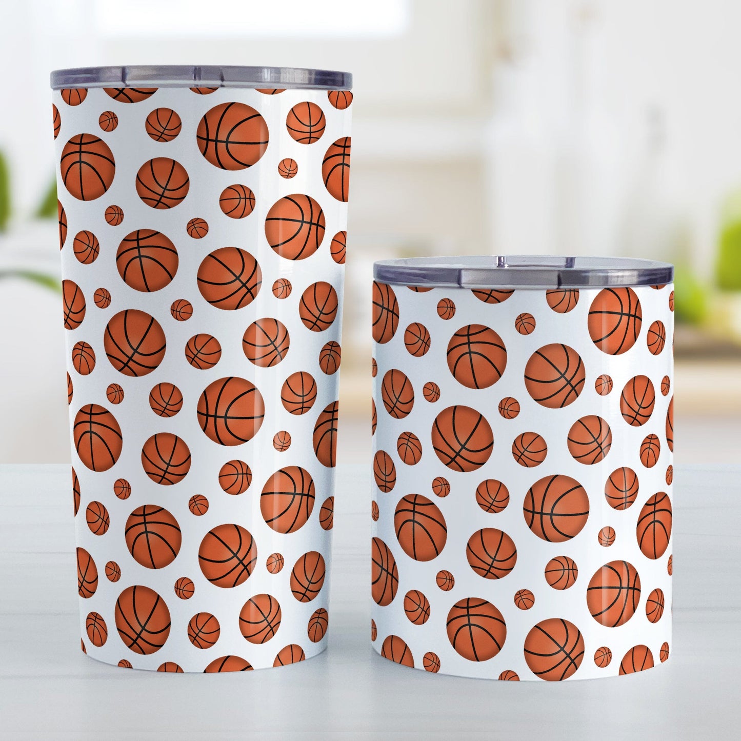 Basketballs Pattern Tumbler Cup (20oz and 10oz) at Amy's Coffee Mugs. A stainless steel tumbler cup designed with basketballs in varying sizes in a pattern that wraps around the cup. Photo shows both sized cups on a table next to each other.