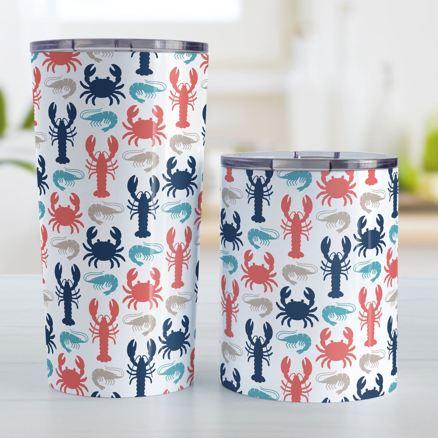 Coastal Crustaceans Tumbler Cup (20oz or 10oz) at Amy's Coffee Mugs. A stainless steel tumbler cup with crabs, lobsters, and shrimp, in colors of ocean navy, coral red, sand beige, and teal, in a pattern that wraps around the cup. Photo shows both sized cups on a table next to each other.