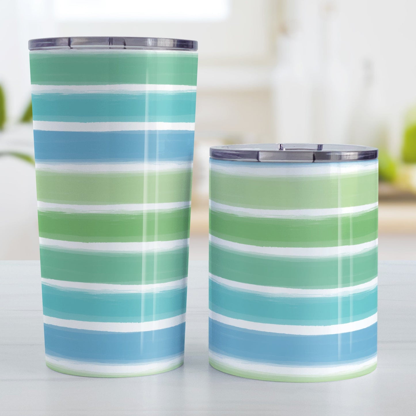 Cool Paint Strokes Tumbler Cups (20oz and 10oz) at Amy's Coffee Mugs. Stainless steel tumbler cups designed with a pattern of horizontal stripes done in a paint strokes illustration in cool colors that wraps around the cups. These cool colors include green, teal, blue tones. Photo shows both sized cups on a table next to each other.