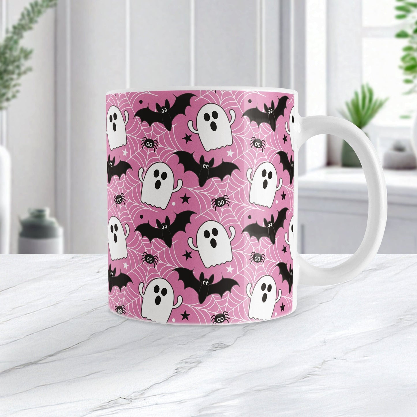 Mug with Halloween-themed design featuring ghosts, bats, and spiders on a pink background.
