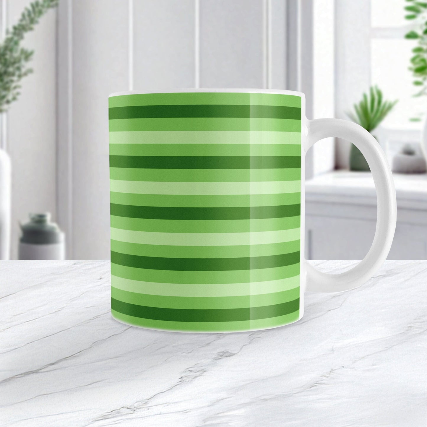 11oz white mug with green stripes in 3 shades in a pattern that wraps around the mug up to the handle, on a marble countertop
