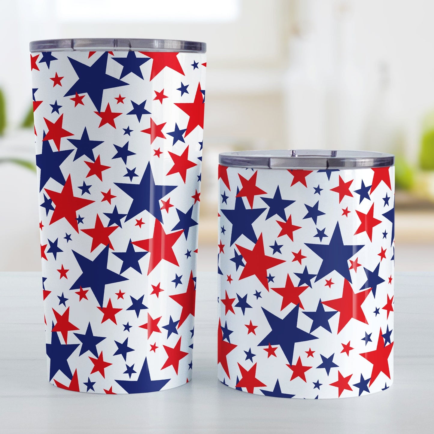 Patriotic Stars Tumbler Cup (20oz or 10oz) at Amy's Coffee Mugs. A stainless steel tumbler cup for the 4th for July (Independence Day) designed with red and blue stars, in varying sizes, over a white background in a pattern that wraps around the cup. Image shows both sized cups next to each other on a table.