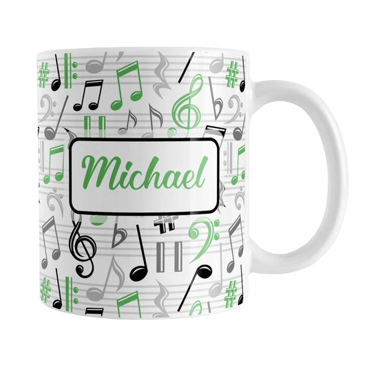 Personalized Green Music Notes Pattern Mug (11oz) at Amy's Coffee Mugs. A ceramic coffee mug designed with music notes and symbols in green, black, and gray in a pattern that wraps around the mug to the handle. Your personalized name is custom printed in a green script font on white over the music pattern design on both sides of the mug.