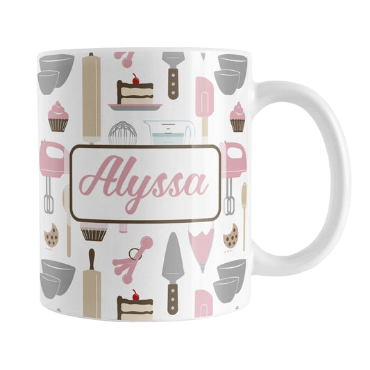 Personalized Pink Baking Pattern Mug (11oz) at Amy's Coffee Mugs. A ceramic coffee mug designed with a pattern of baking tools like spatulas, whisks, mixers, bowls, and spoons, with cookies, cupcakes, and cake all in a pink, gray, brown, and beige color scheme that wraps around the mug. Your name is printed in a pink script font on both sides of the mug over the cute baking pattern.