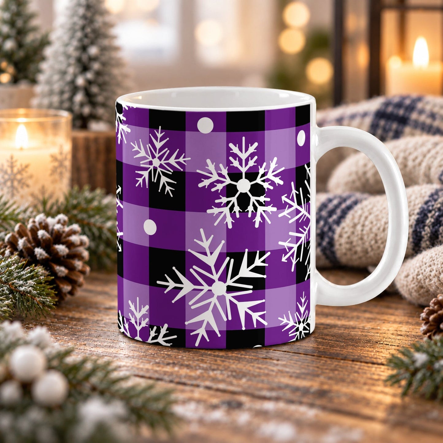 11 oz purple and black buffalo plaid snowflake mug with large white snowflakes and snowy dot accents, on a wooden table with winter decor around it including pine cones, pine boughs, candles, and a cozy plaid blanket.