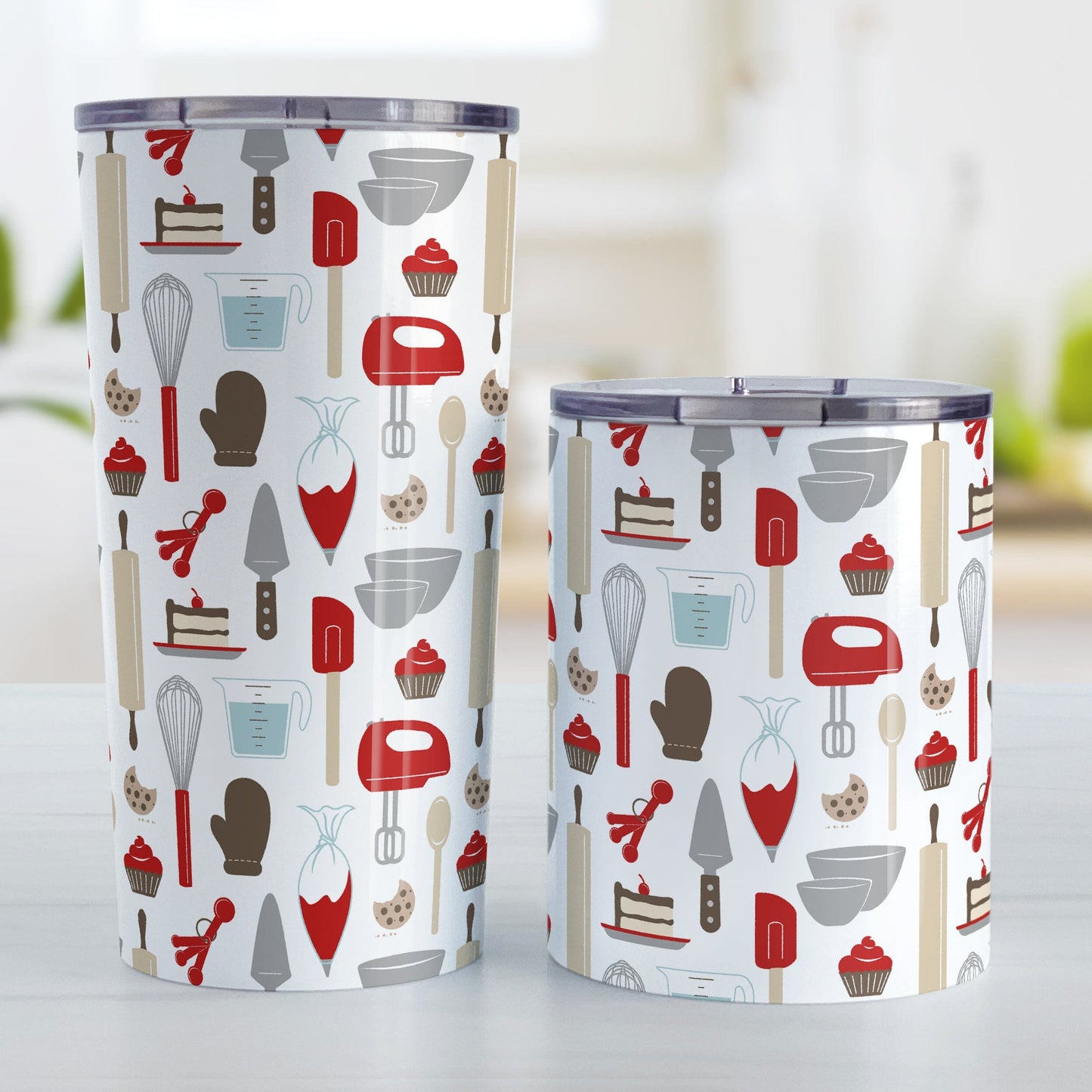 Red Baking Pattern Tumbler Cups (20oz or 10oz) at Amy's Coffee Mugs. Stainless steel tumbler cups designed with a pattern of baking tools like spatulas, whisks, mixers, bowls, and spoons, with cookies, cupcakes, and cake all in a red, gray, brown, and beige color scheme that wraps around the cups. Photo shows both sized cups on a table next to each other.