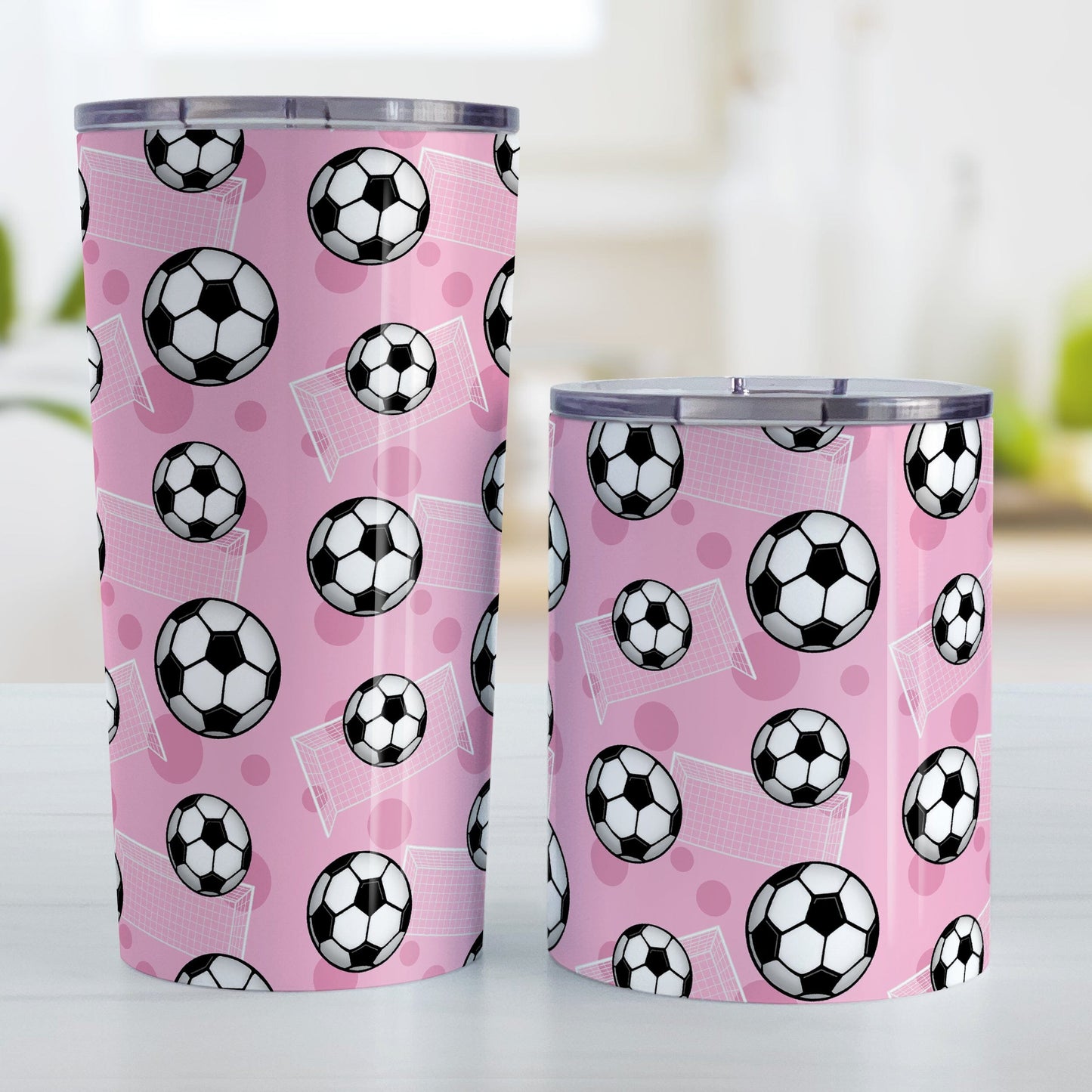 Soccer Ball and Goal Pattern Pink Tumbler Cup (20oz and 10oz) at Amy's Coffee Mugs. Stainless steel insulated tumbler cups designed with a pattern of soccer balls and goals over a pink background that wraps around the cups. These pink soccer tumbler cups are perfect for people who love or play soccer. Photo shows both sized cups next to each other.
