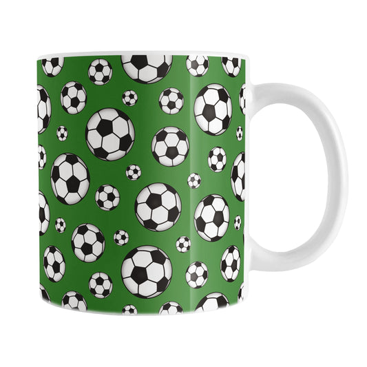 11oz white ceramic mug with a design of soccer balls over dark green