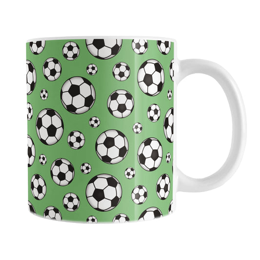 11oz white ceramic mug with a design of soccer balls over green