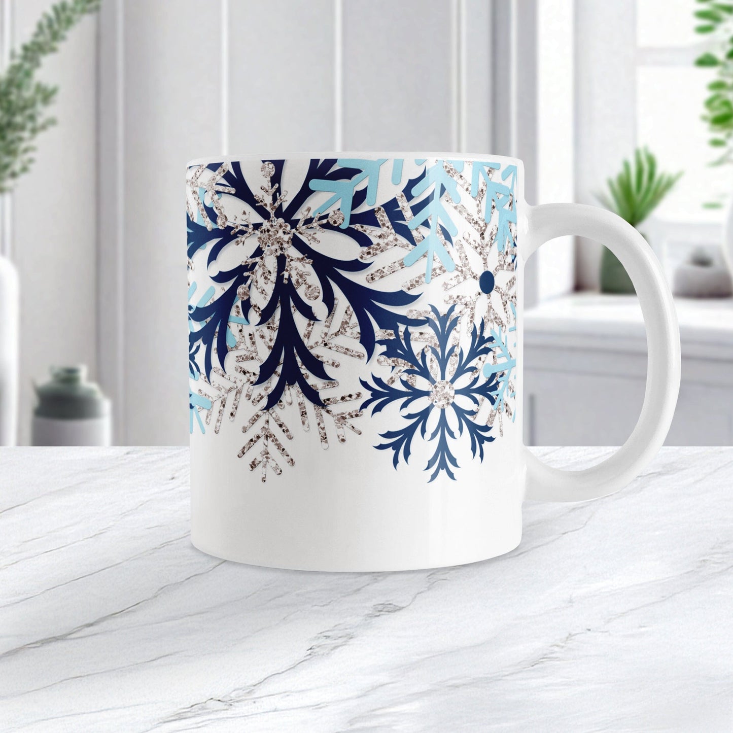Winter Blue Silver Snowflake Mug (11oz) at Amy's Coffee Mugs. A ceramic coffee mug with navy blue, aqua blue, and silver-colored glitter-illustrated snowflakes along the top, cascading down most of the mug, over white. This wintry snowflake design wraps around the mug up to the handle. Image shows the mug on a white marble countertop.