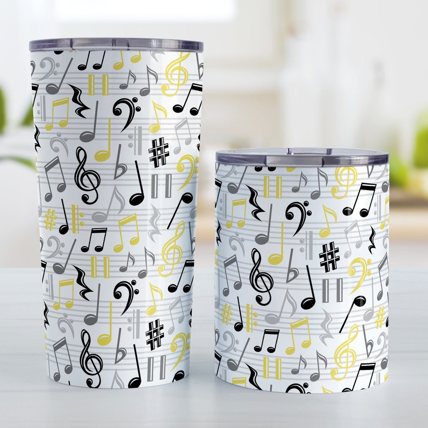 Yellow Music Notes Pattern Tumbler Cups (20oz or 10oz) at Amy's Coffee Mugs. Stainless steel tumbler cups designed with music notes and symbols in yellow, black, and gray in a pattern that wraps around the cups. Photo shows both sized cups on a table next to each other.