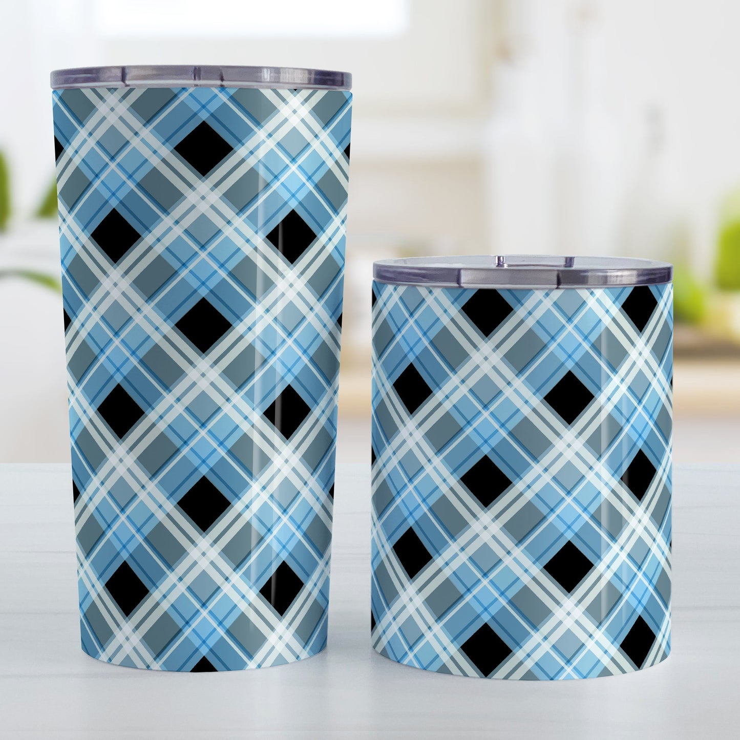 Alternative Black and Blue Plaid Tumbler Cup (20oz and 10oz) at Amy's Coffee Mugs. Stainless steel insulated tumbler cups designed with a diagonal blue, black, and white plaid pattern that wraps around the cups. Tumbler cups designed for someone who loves plaid patterns and the colors blue and black together. Photo shows both sized cups next to each other.