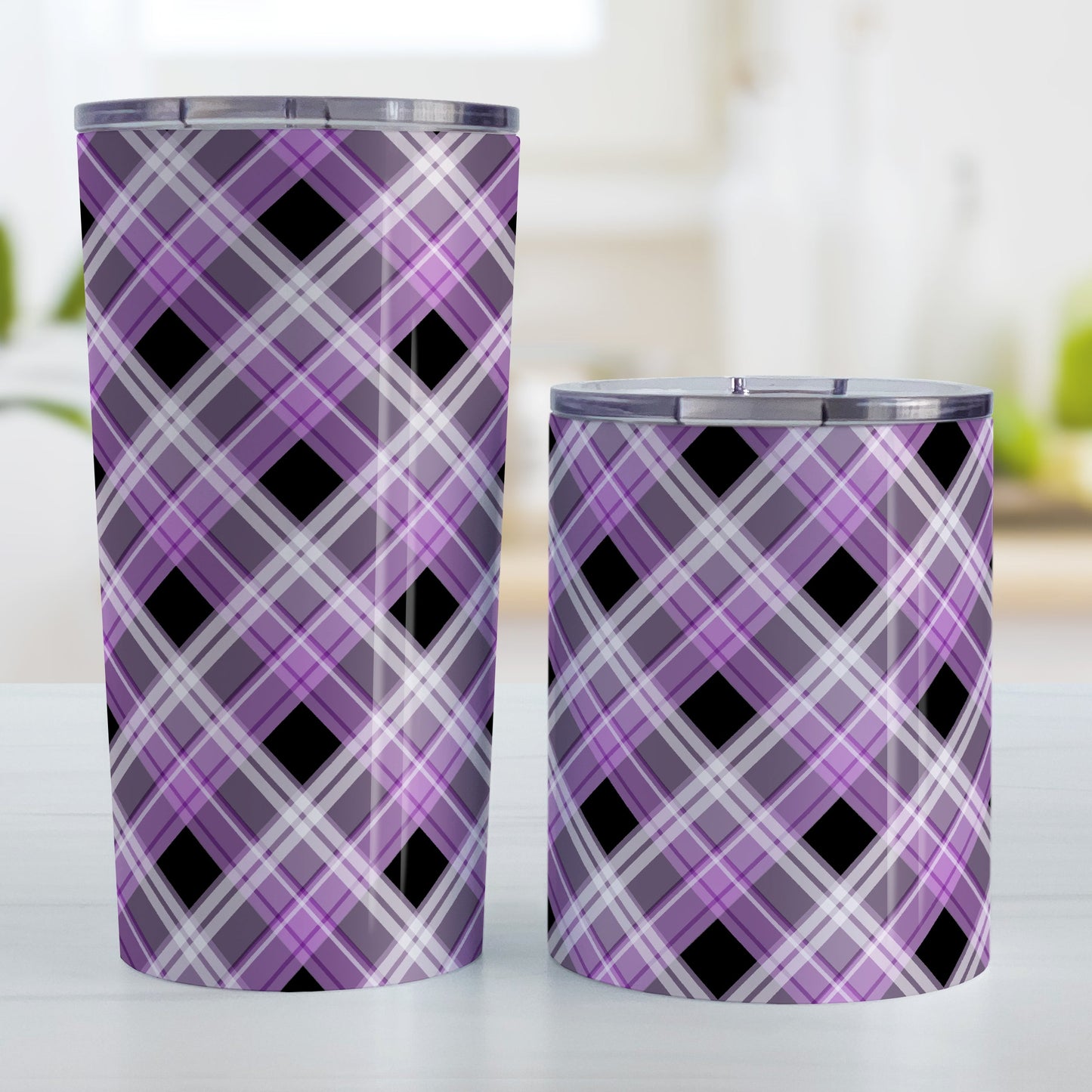 Alternative Black and Purple Plaid Tumbler Cup (20oz and 10oz, stainless steel insulated) at Amy's Coffee Mugs. Tumbler cups designed with a diagonal purple, black, and white plaid pattern that wraps around the insulated tumbler cups. Heavy-duty tumblers designed for someone who loves plaid patterns and the colors purple and black. Photo shows both sized cups next to each other.