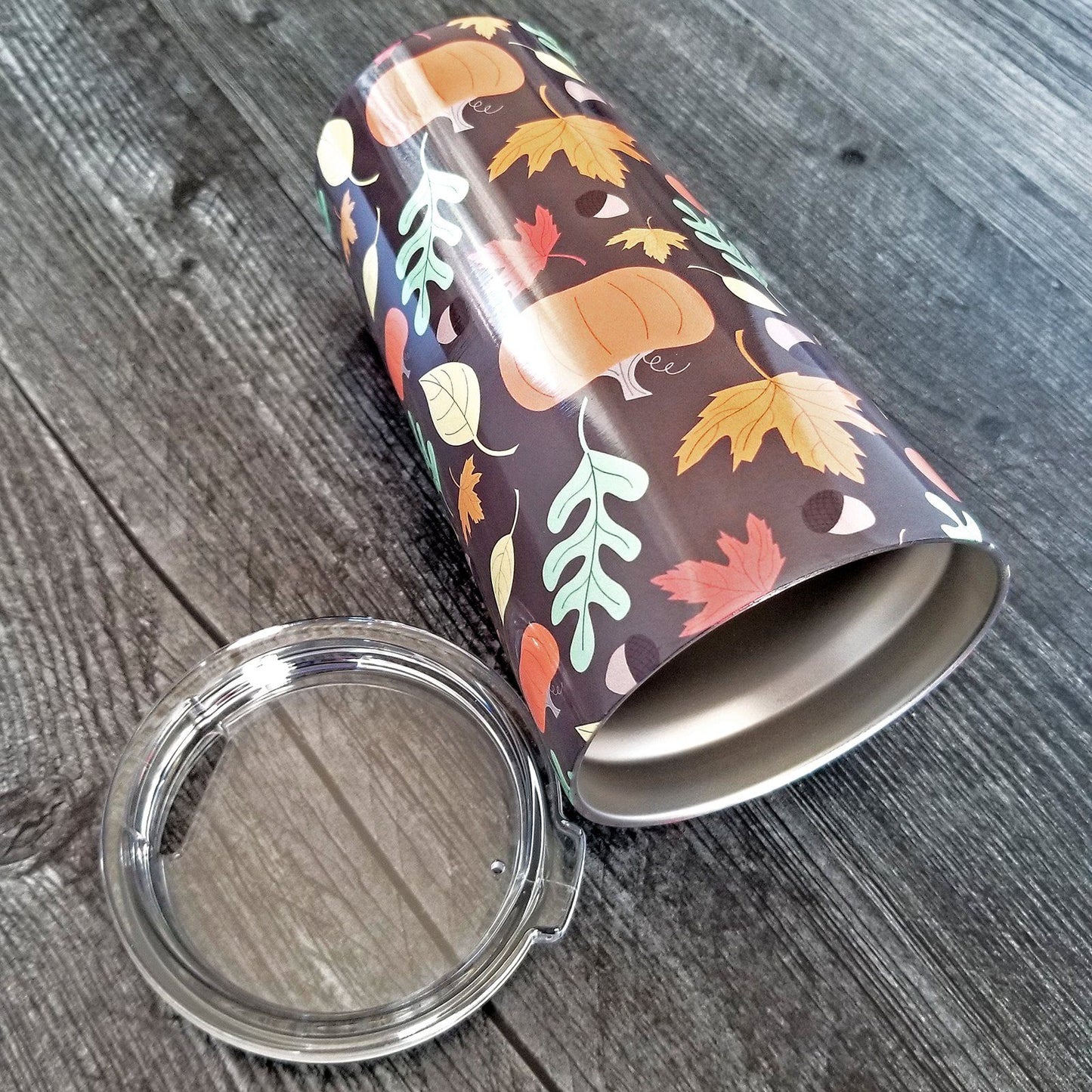 Autumn Pumpkins and Leaves Pattern - Fall Tumbler Cup (20oz, on weathered wood) at Amy's Coffee Mugs. A tumbler cup designed with a pattern of pumpkins, acorns, and leaves in orange, yellow, and green over a brown background color that wraps around the cup.