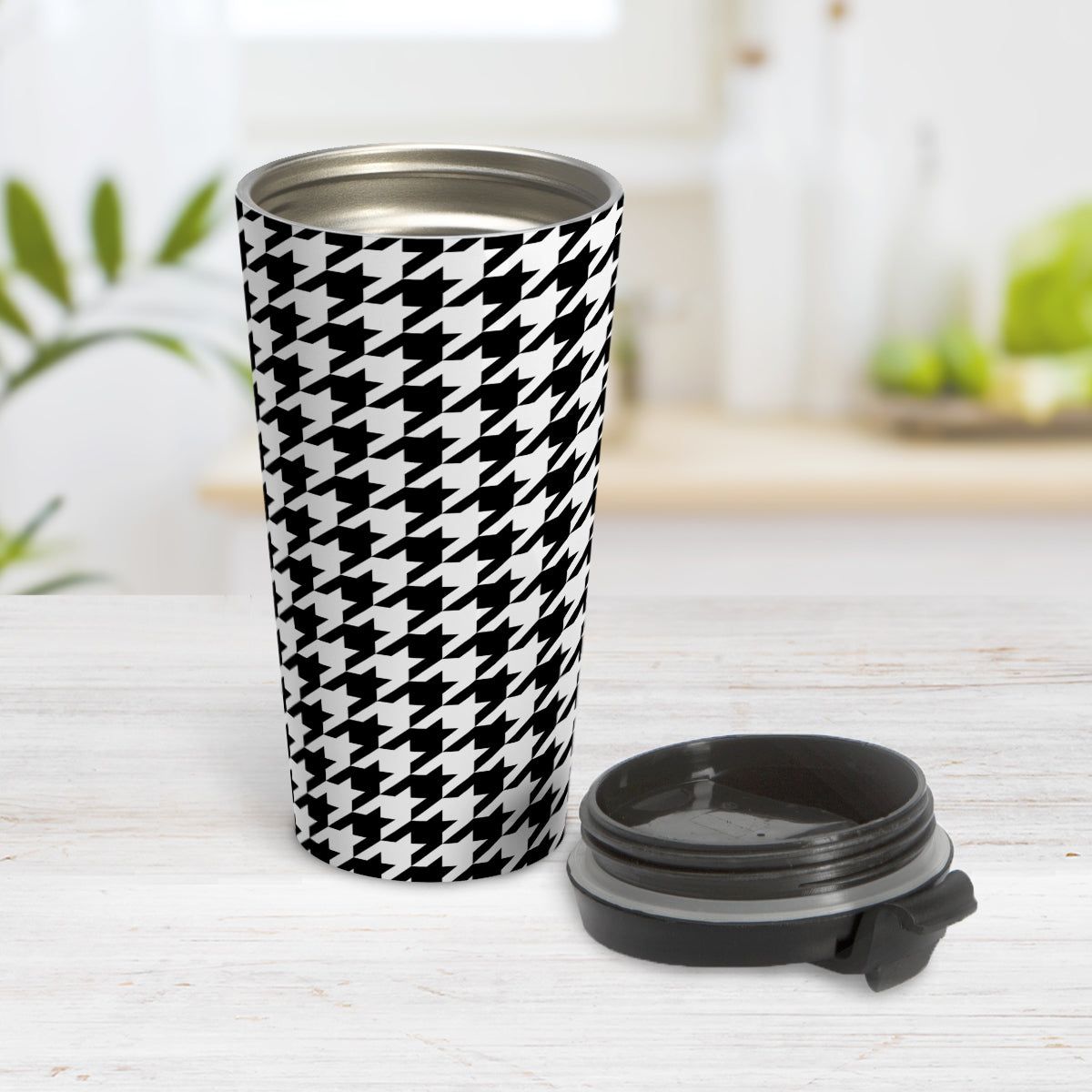 Black and White Houndstooth Travel Mug (15oz) at Amy's Coffee Mugs. A travel mug designed with a black and white houndstooth (dogtooth) pattern that wraps around the travel mug. Photo shows the mug open on a table with the lid next to it.