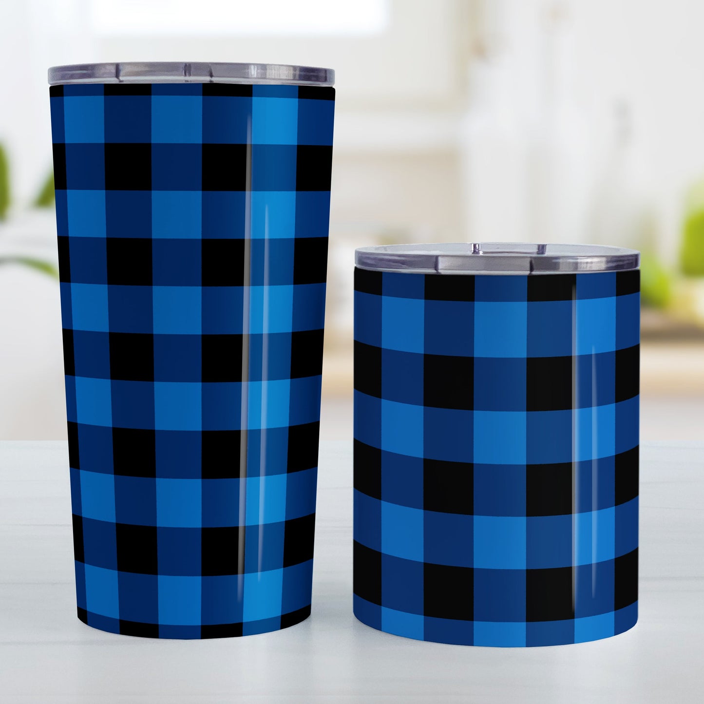 Blue and Black Buffalo Plaid Tumbler Cup (20oz and 10oz, stainless steel insulated) at Amy's Coffee Mugs. Tumbler cups designed with a blue and black buffalo plaid (buffalo check) pattern that wraps around the cups. Photo shows both sized cups on a table next to each other.