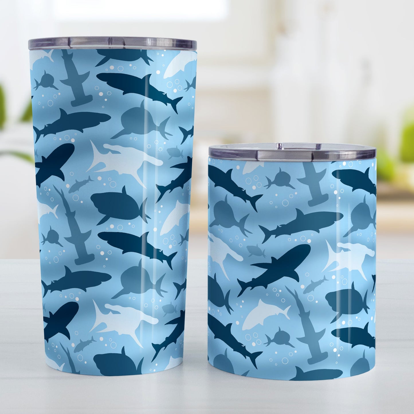 Blue Frenzy Sharks Tumbler Cup (20oz and 10oz) at Amy's Coffee Mugs. Stainless steel insulated tumbler cups designed with a pattern of sharks in different shades of blue, in a frenzy deep beneath the water, that wraps around the cups. Perfect for people who love sharks or are looking for the perfect shark gift. Photo shows both sized cups next to each other.