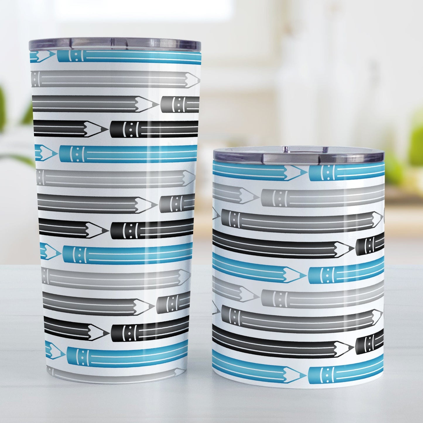 Blue Gray Black Pencils Pattern Tumbler Cups (20oz or 10oz) at Amy's Coffee Mugs. Stainless steel tumbler cups designed with horizontal pencils in blue, gray, and black, stacked in a pattern that wraps around the cups. Photo shows both sized cups next to each other on a table.