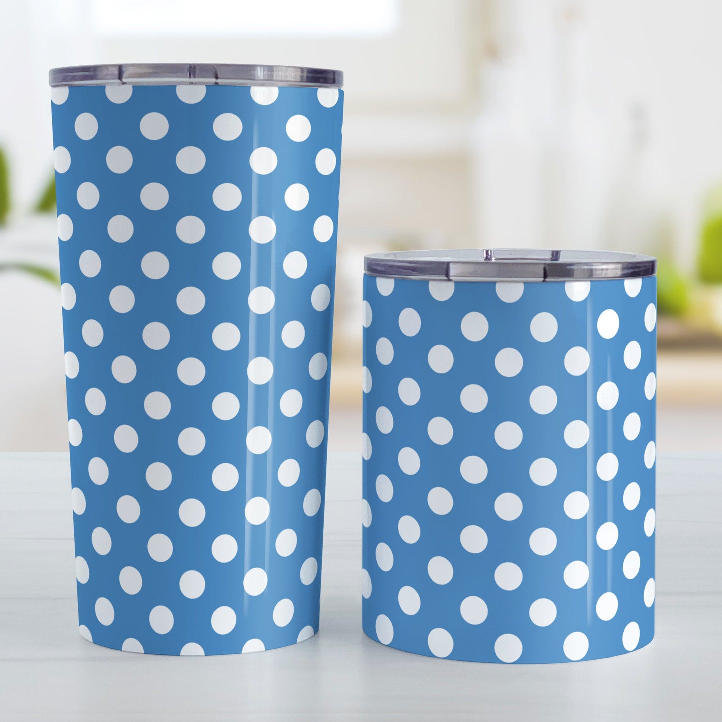 Blue Polka Dot Tumbler Cup (20oz and 10oz, stainless steel insulated) at Amy's Coffee Mugs. Cups designed with a pattern of white polka dots over a blue background color that wraps around the cups. Photo shows both sized cups on a table next to each other.