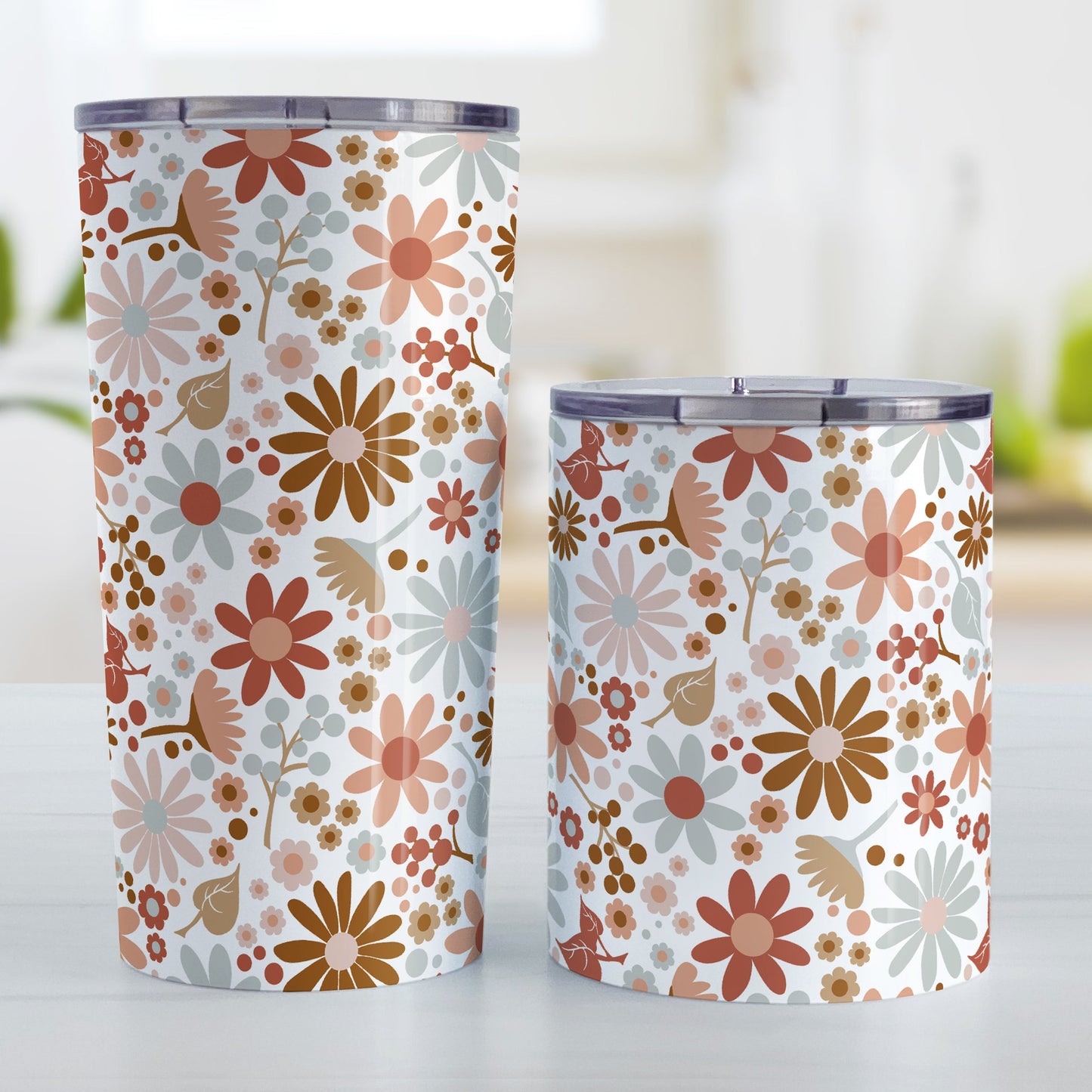 Boho Summer Flowers Tumbler Cup (20oz and 10oz, stainless steel insulated) at Amy's Coffee Mugs. Tumbler cups designed with flowers and leaves in soothing desert boho colors in a pretty floral pattern that wraps around the cups. Photo shows both sized cups on a table next to each other.