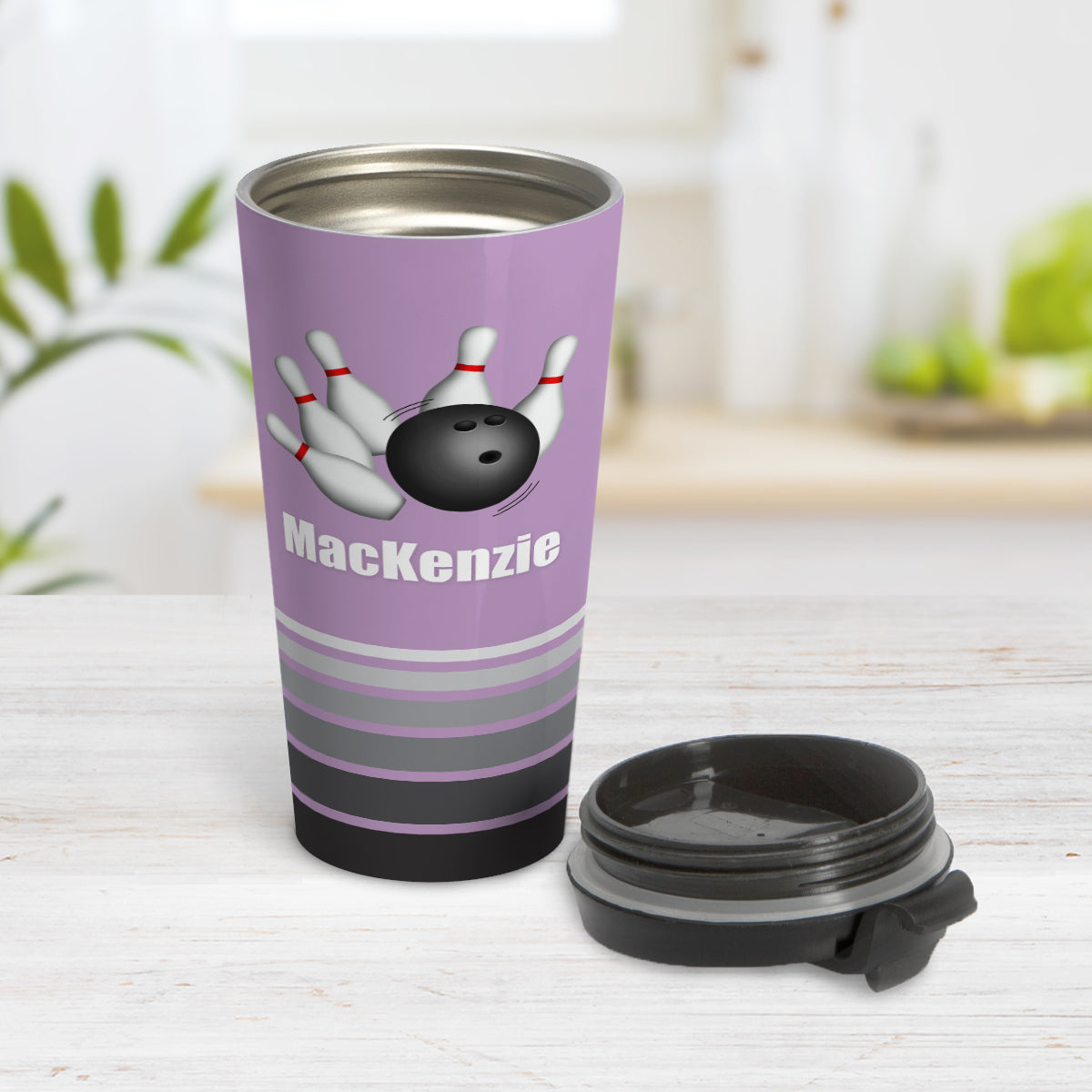 Bowling Ball and Pins Purple - Personalized Bowling Travel Mug (15oz) at Amy's Coffee Mugs. A travel mug designed with an illustration of a bowling ball striking bowling pins over a purple background color that wraps around the travel mug. Along the bottom of the mug are gray stripes in varying shades creating a dynamic look. Your custom name is printed in white below the bowling ball and pins. Photo show the mug open on a table with its lid beside it.