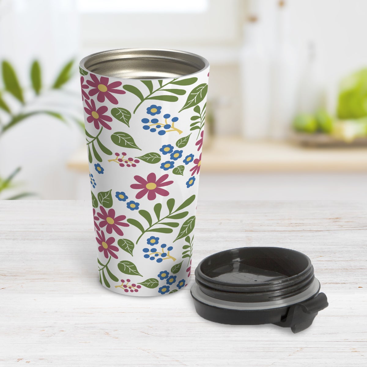 Burgundy Blue Green Flowers Pattern Travel Mug (15oz) at Amy's Coffee Mugs. A travel mug designed with pretty flowers in burgundy and blue with green leaves in a pattern that wraps around the travel mug. Photo shows the mug open on a table with the lid beside it.
