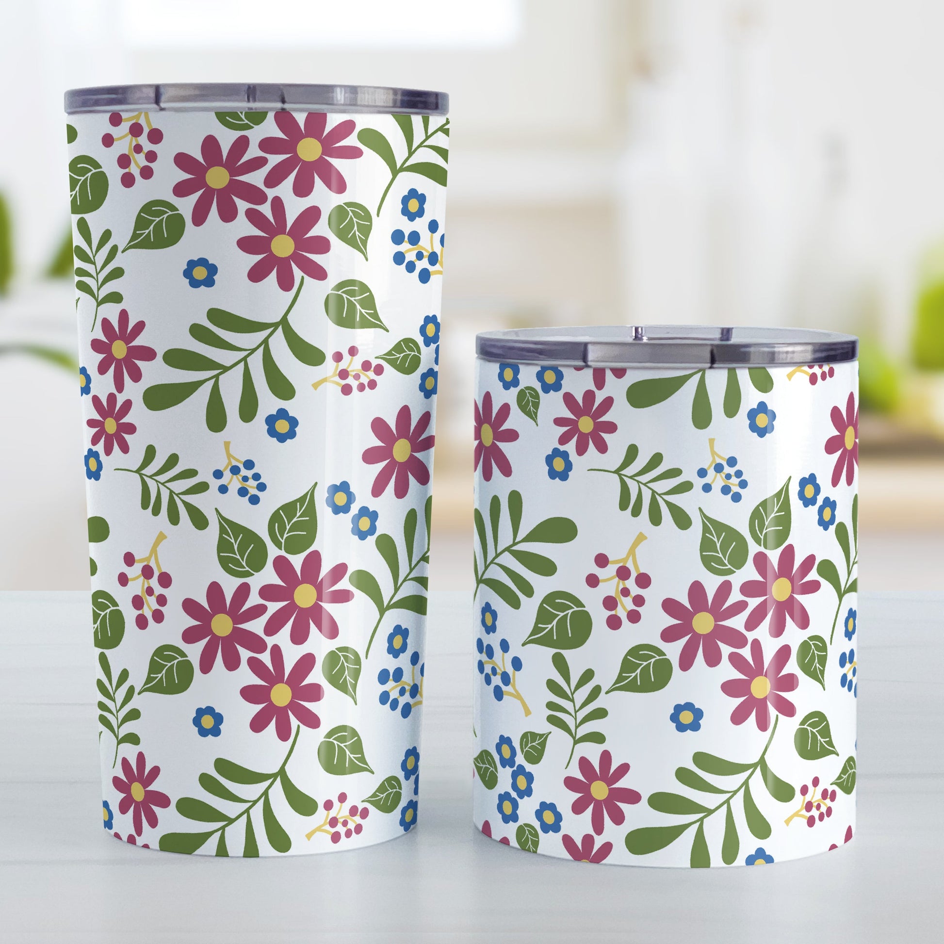Burgundy Blue Green Flowers Pattern Tumbler Cup (20oz and 10oz, stainless steel insulated) at Amy's Coffee Mugs. Tumbler cups designed with pretty flowers in burgundy and blue with green leaves in a pattern that wraps around the cups. Photo shows both sized cups on a table next to each other.