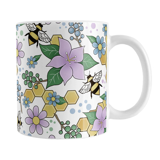Colorful Purple Floral Bee Pattern Mug (11oz) at Amy's Coffee Mugs. A ceramic coffee mug designed with purple, blue, and green flowers and leaves with bees and golden yellow honeycomb pieces in a pattern that wraps around the mug up to the handle.