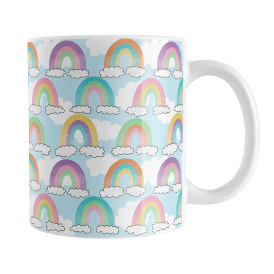 Colorful Rainbows Sky Pattern Mug (11oz) at Amy's Coffee Mugs. A ceramic coffee mug designed with an illustration of different rainbows with three different semi-faded colors each sitting on clouds, over a blue sky with white clouds in the background that wraps around the mug up to the handle.