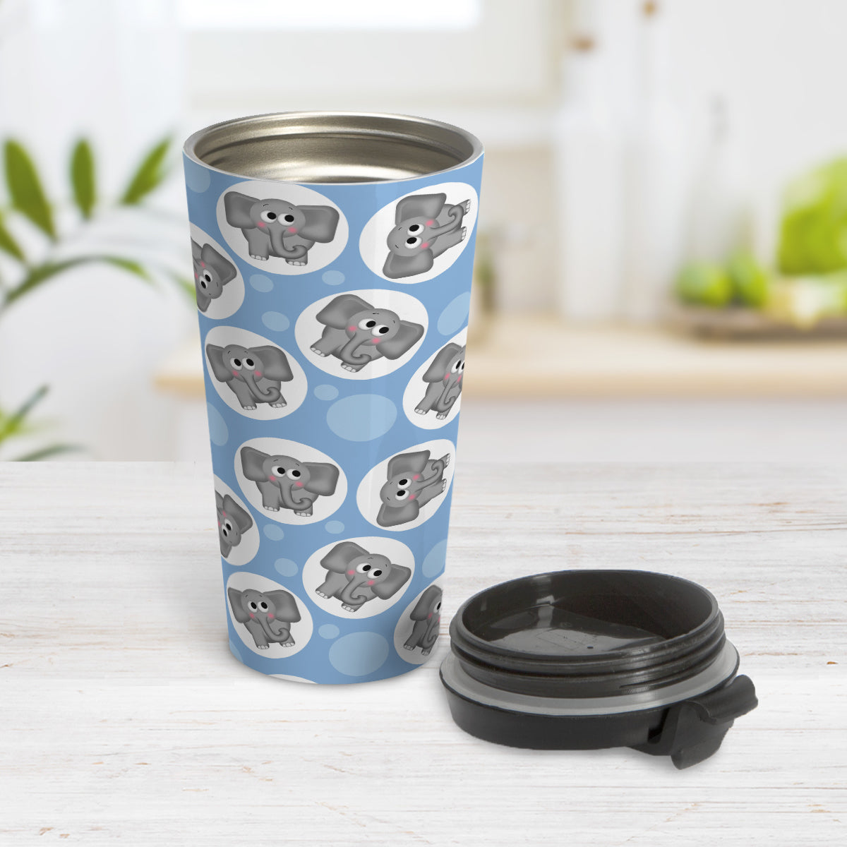 Cute Blue Elephant Pattern Travel Mug (15oz) at Amy's Coffee Mugs. A travel mug designed with cute and affectionate gray elephants in white circles scattered over a blue background color in a pattern that wraps around the travel mug. Photo shows the mug open on a table with the lid beside it.