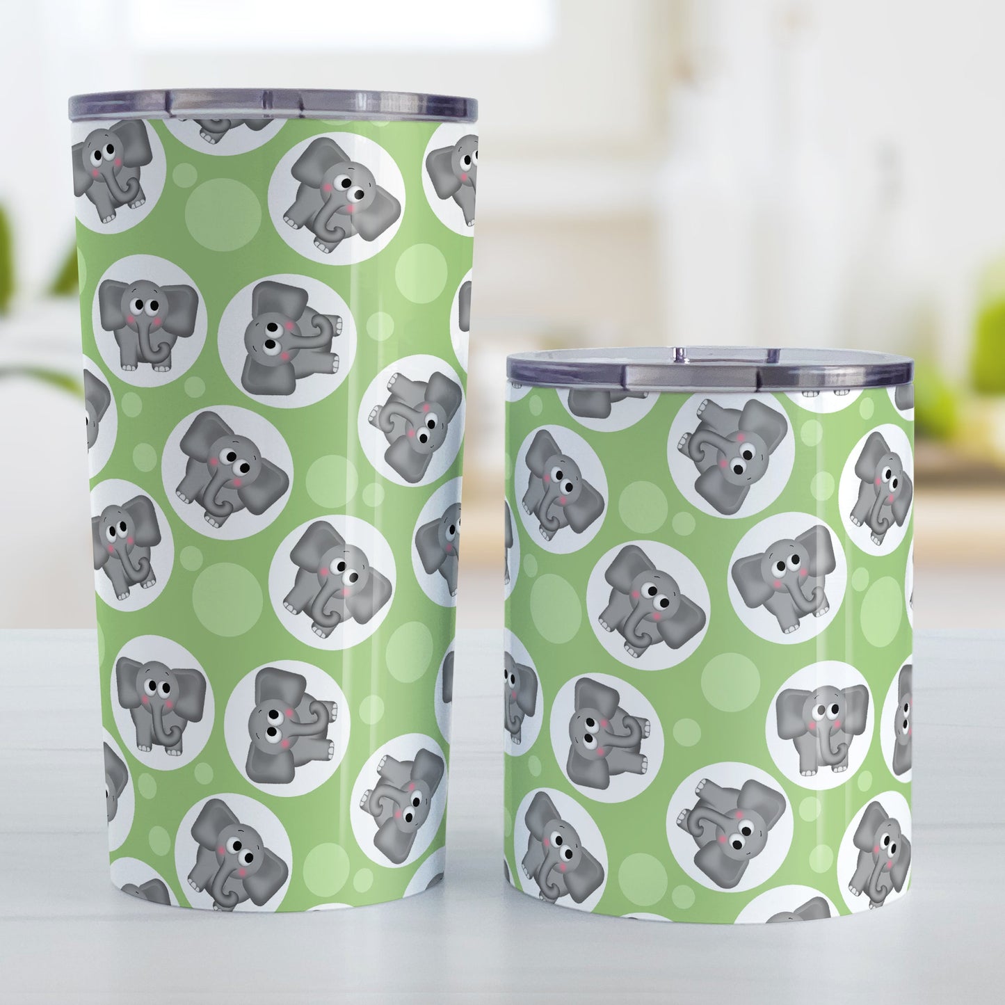 Cute Green Elephant Pattern Tumbler Cup (20oz and 10oz, stainless steel insulated) at Amy's Coffee Mugs. Tumbler cups designed with cute and affectionate gray elephants in white circles scattered over a green background color in a pattern that wraps around the cups. Photo shows both sized cups on a table next to each other.