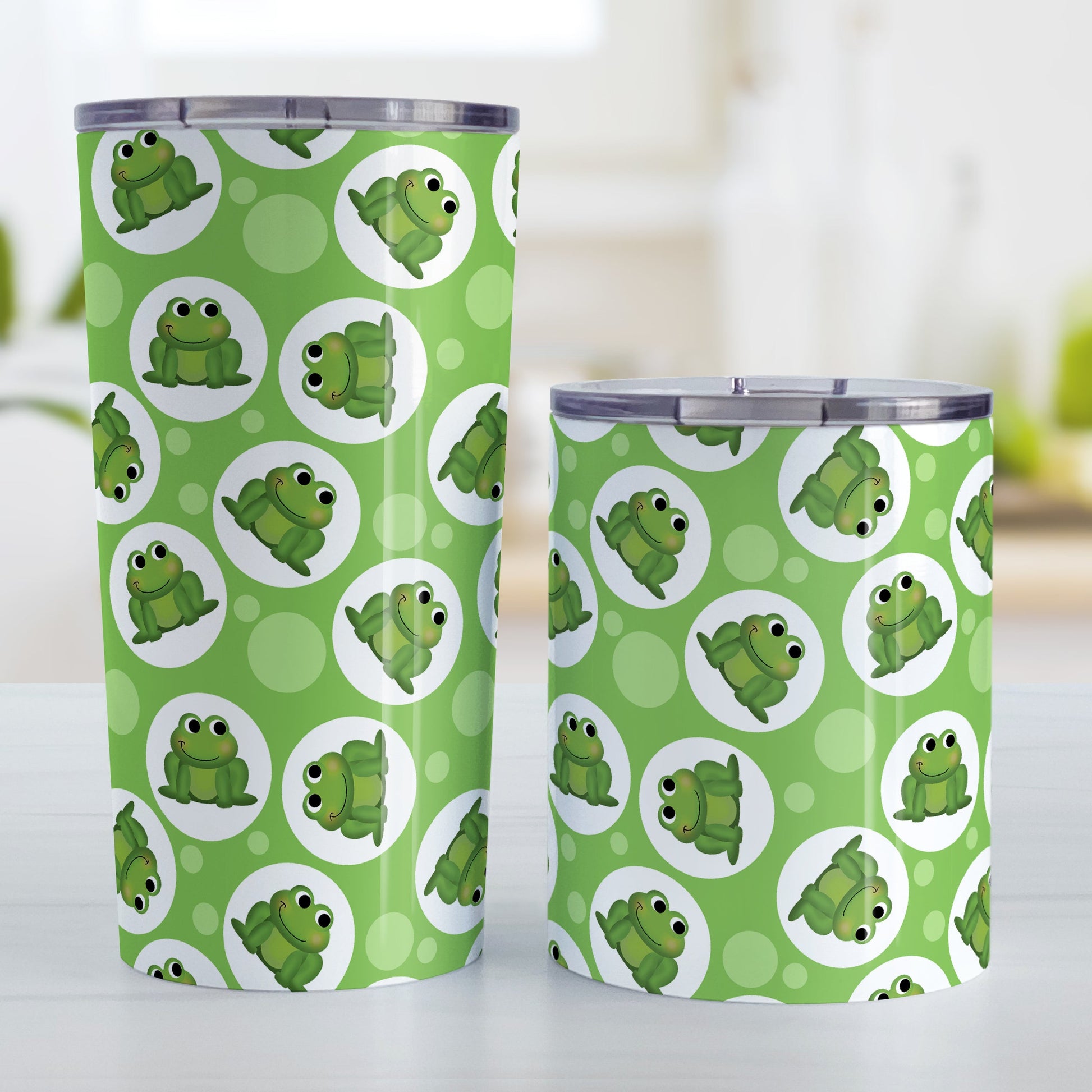Cute Green Frog Pattern Tumbler Cup (20oz and 10oz, stainless steel insulated) at Amy's Coffee Mugs. Tumbler cups designed with cute and smiling green frogs in white circles scattered over a green background color in a pattern that wraps around the cups. Photo shows both sized cups on a table next to each other.