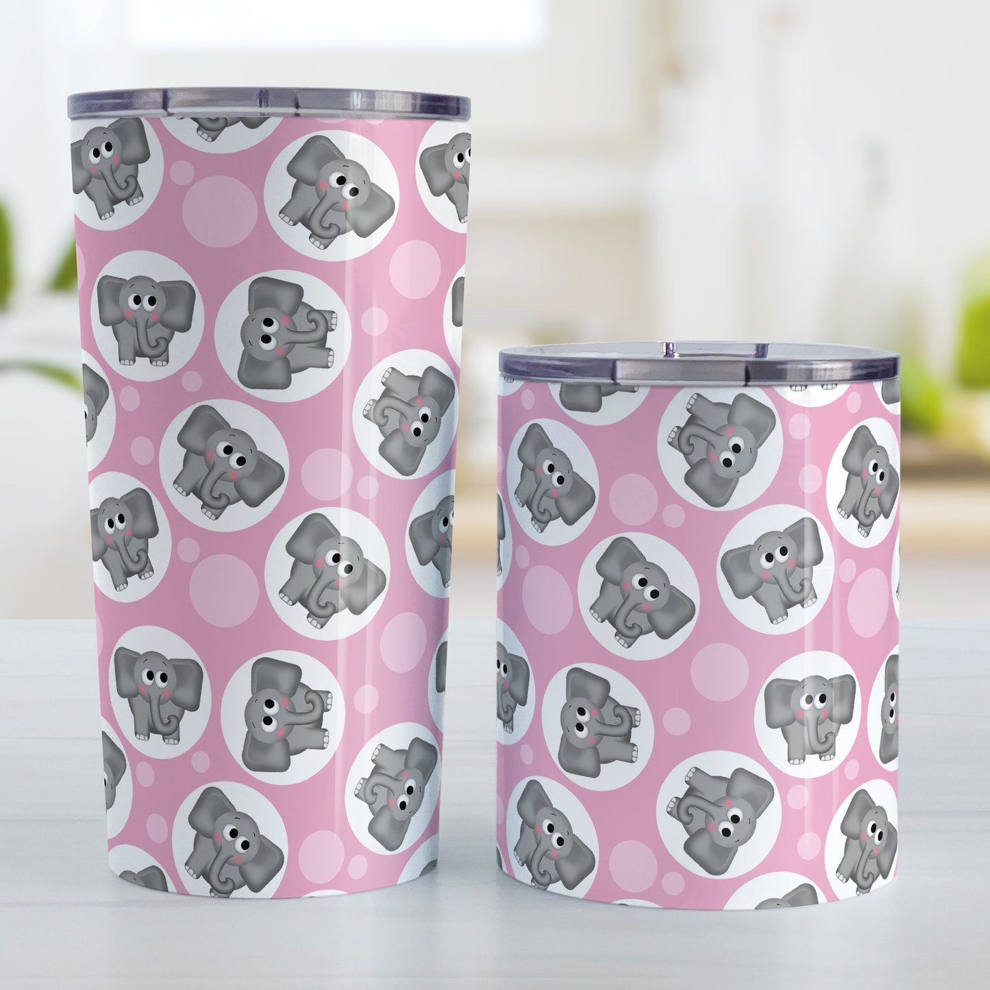 Cute Pink Elephant Pattern Tumbler Cup (20oz an 10oz, stainless steel insulated) at Amy's Coffee Mugs. Tumbler cups designed with cute and affectionate gray elephants in white circles scattered over a pink background color in a pattern that wraps around the cups. Photo shows both sized cups on a table next to each other.