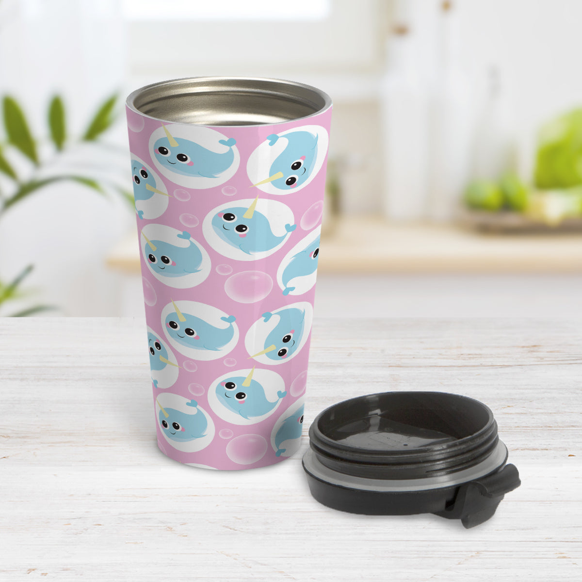 Cute Pink Narwhal Bubble Pattern Travel Mug (15oz) at Amy's Coffee Mugs. A travel mug designed with cute light blue narwhals in white circles and with bubbles scattered over a pink background color in a pattern that wraps around the travel mug. Photo shows the mug open on a table with the lid next to it.