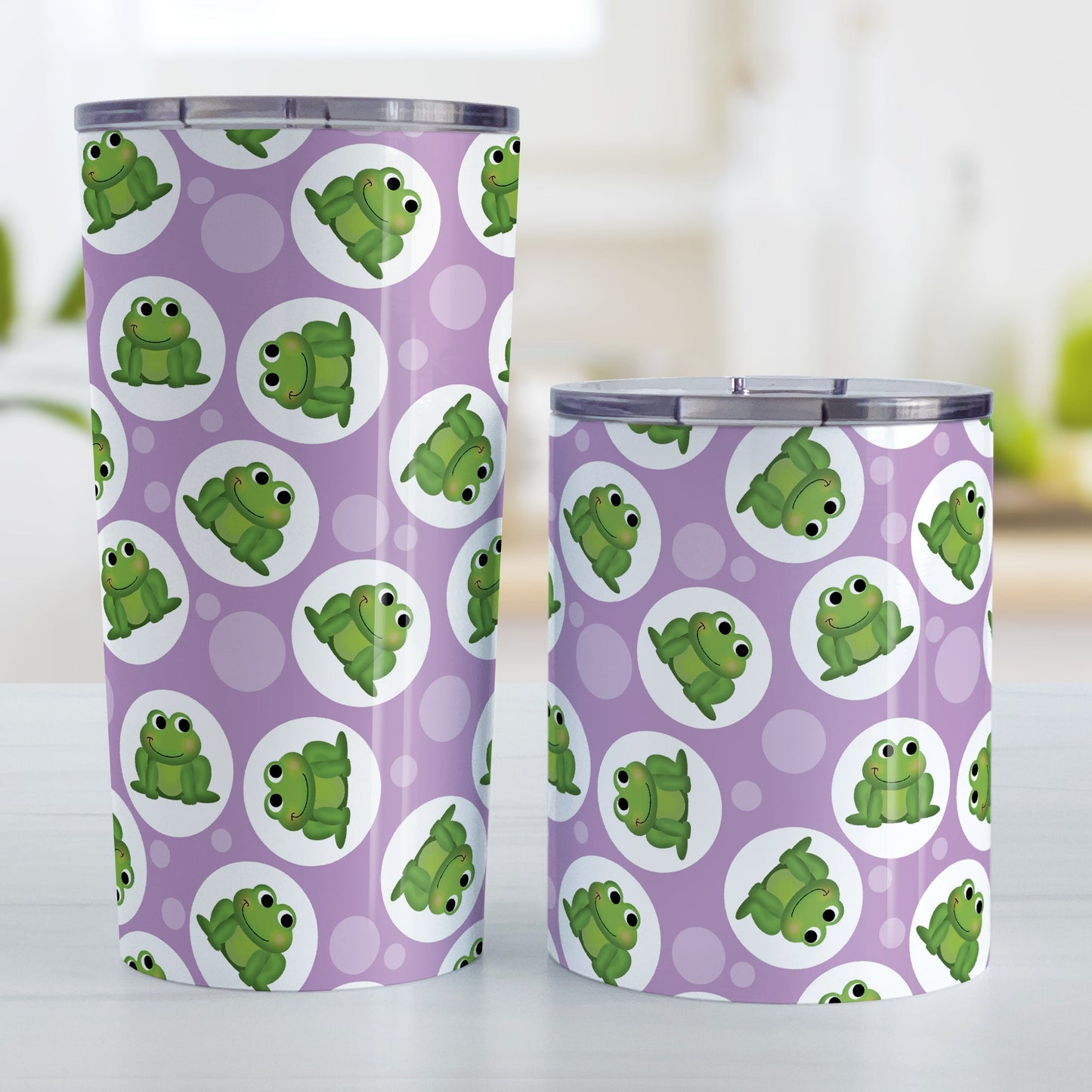 Cute Purple Frog Pattern Tumbler Cup (20oz and 10oz, stainless steel insulated) at Amy's Coffee Mugs. Tumbler cups designed with cute and smiling green frogs in white circles scattered over a purple background color in a pattern that wraps around the cups. Photo shows both sized cups on a table next to each other.