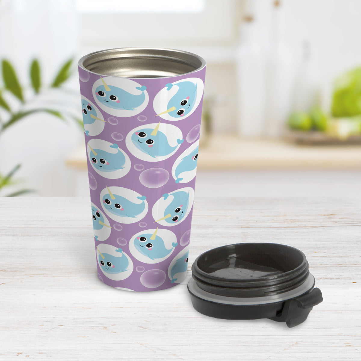 Cute Purple Narwhal Bubble Pattern Travel Mug (15oz) at Amy's Coffee Mugs. A travel mug designed with cute light blue narwhals in white circles and with bubbles scattered over a purple background color in a pattern that wraps around the travel mug. Photo shows the mug open on a table with its lid beside it.