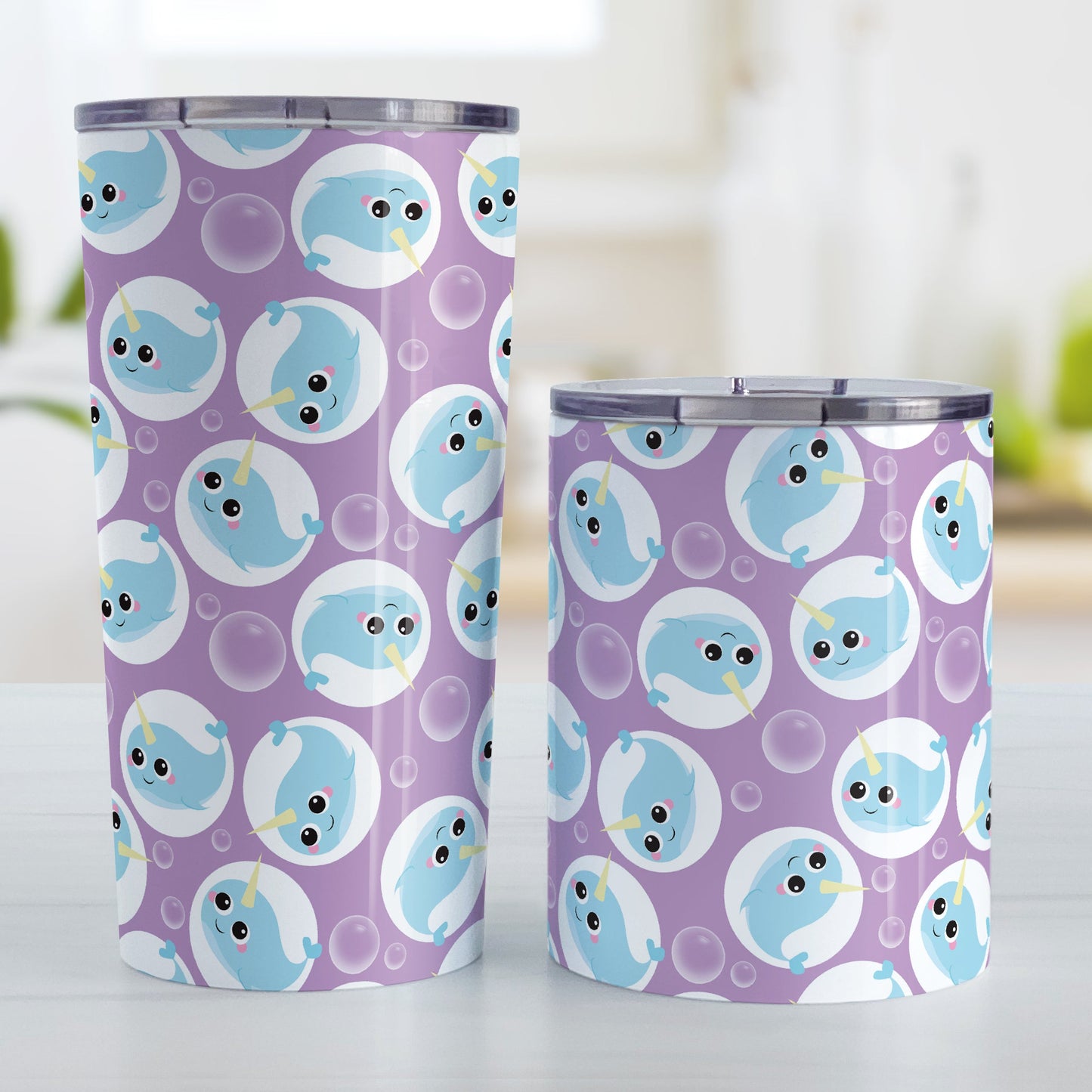 Cute Purple Narwhal Bubble Pattern Tumbler Cup (20oz on 10oz, stainless steel insulated) at Amy's Coffee Mugs. A tumbler cup designed with cute light blue narwhals in white circles and with bubbles scattered over a purple background color in a pattern that wraps around the cup. Photo shows both sized cups on a table next to each other.
