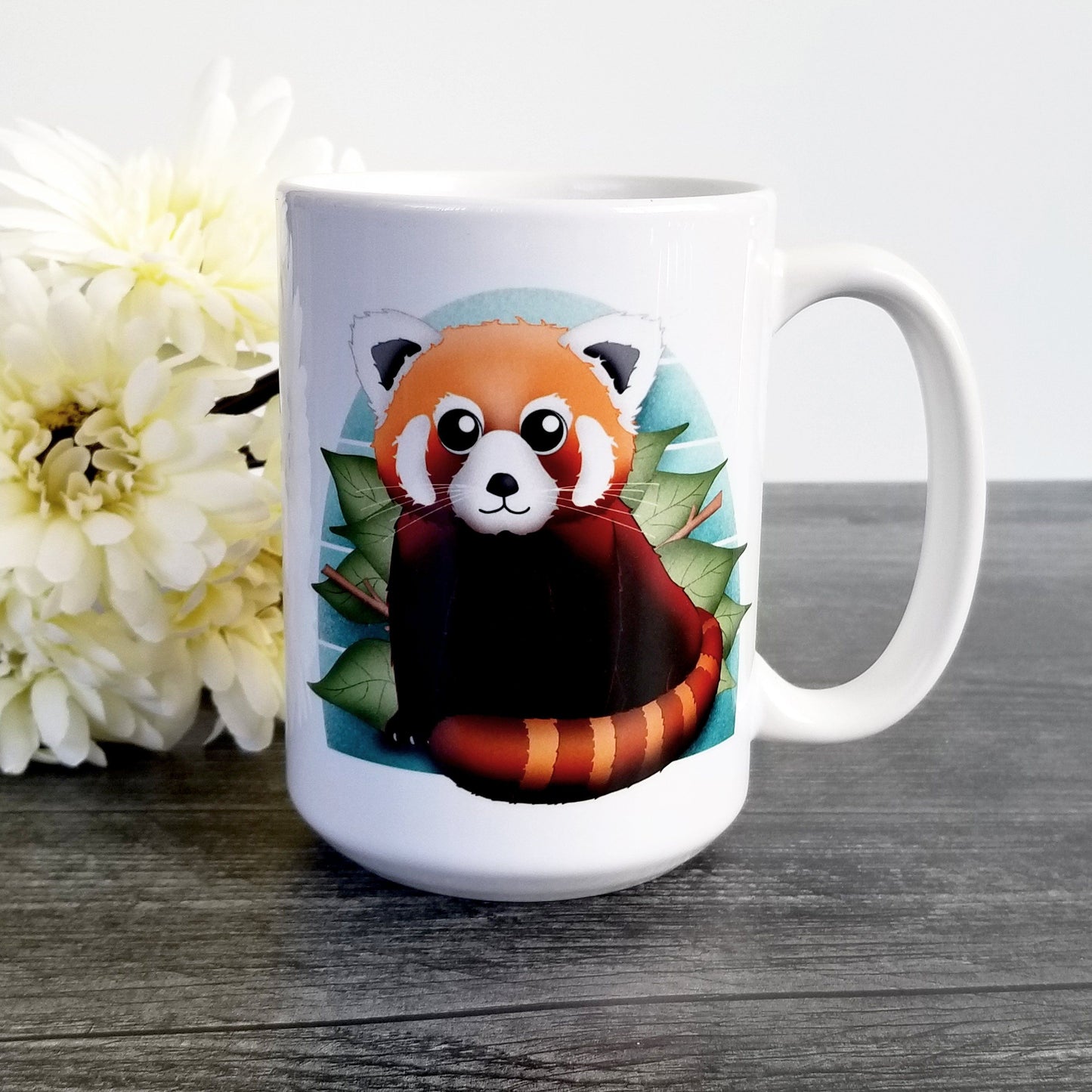 Cute Red Panda Mug (15oz, on weathered wood next to flowers) at Amy's Coffee Mugs. A ceramic coffee mug designed with an illustration of a lovable and cute red panda over a green leaf and blue background design on both sides of the mug.