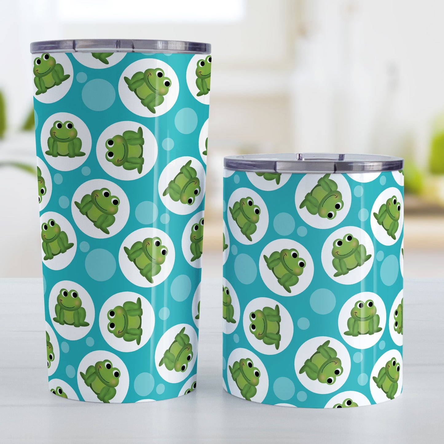 Cute Turquoise Frog Pattern Tumbler Cup (20oz and 10oz, stainless steel insulated) at Amy's Coffee Mugs. Tumbler cups designed with cute and smiling green frogs in white circles scattered over a turquoise background color in a pattern that wraps around the cups. Photo shows both sized cups on a table next to each other.