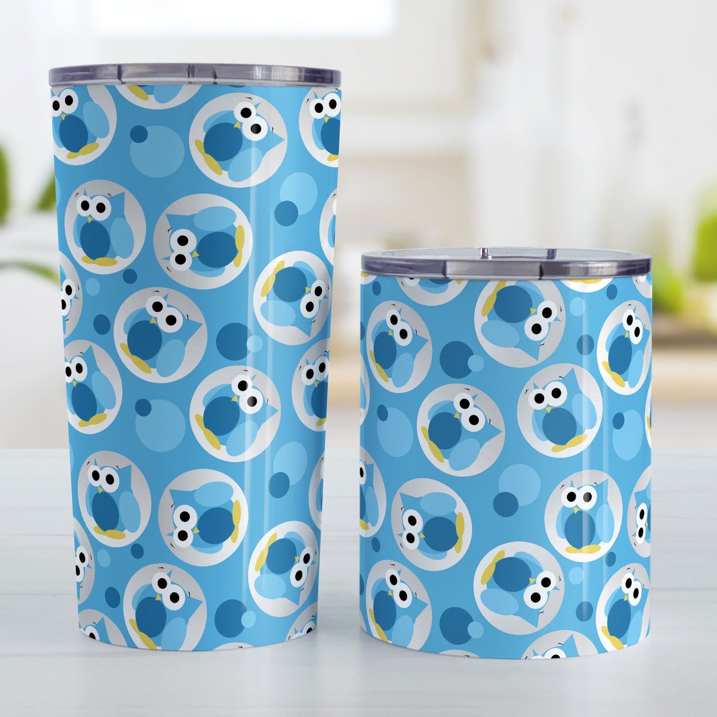 Funny Cute Blue Owl Pattern Tumbler Cup (20oz and 10oz, stainless steel insulated) at Amy's Coffee Mugs. A tumbler cup designed with a pattern of funny and cute blue owls in a light gray circles scattered over a blue background color that wraps around the cup. Photo shows both sized cups on a table next to each other.