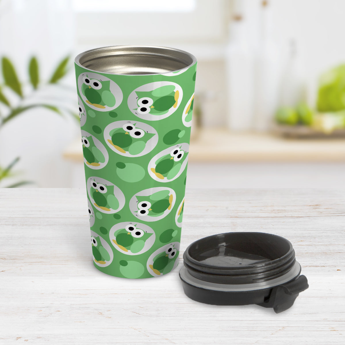Funny Cute Green Owl Pattern Travel Mug (15oz) at Amy's Coffee Mugs. A travel mug designed with a pattern of funny and cute green owls in a light gray circles scattered over a green background color that wraps around the travel mug. Photo shows the mug open on a table with its lid beside it.