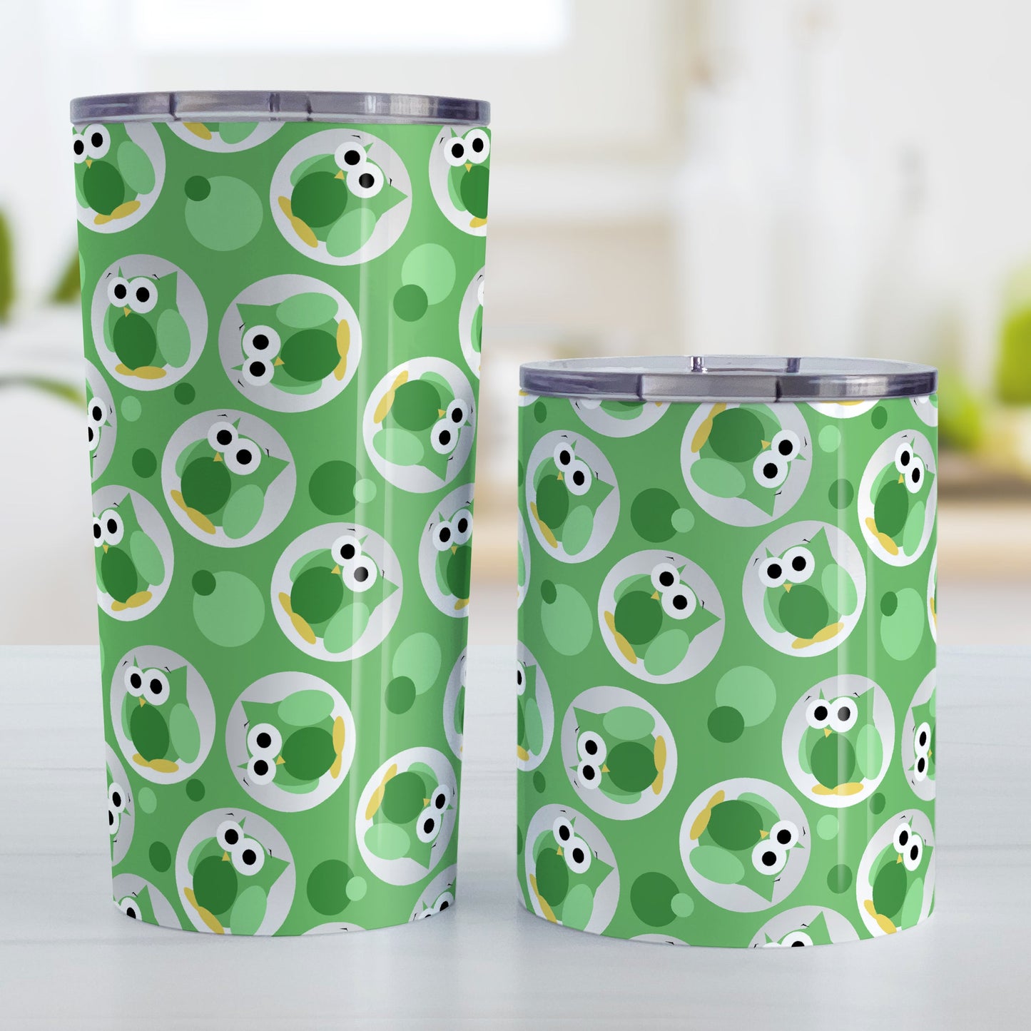 Funny Cute Green Owl Pattern Tumbler Cup (20oz and 10oz, stainless steel insulated) at Amy's Coffee Mugs. A tumbler cup designed with a pattern of funny and cute green owls in a light gray circles scattered over a green background color that wraps around the cup. Photo shows both sized cups on a table next to each other.
