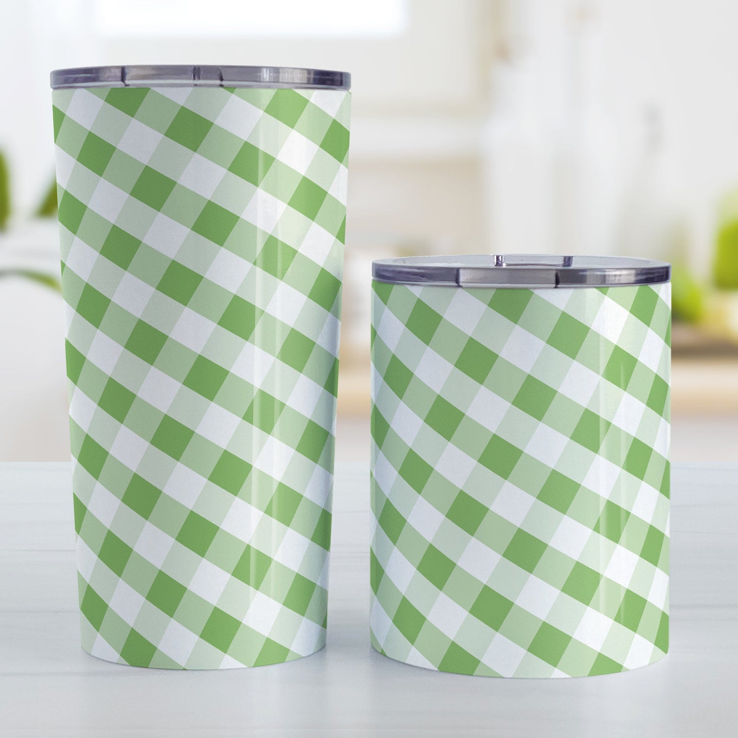 Green Gingham Tumbler Cup (20oz and 10oz, stainless steel insulated) at Amy's Coffee Mugs. A tumbler cup designed with a slanted green and white gingham pattern that wraps around the cup. Photo shows both sized cups on a table next to each other.
