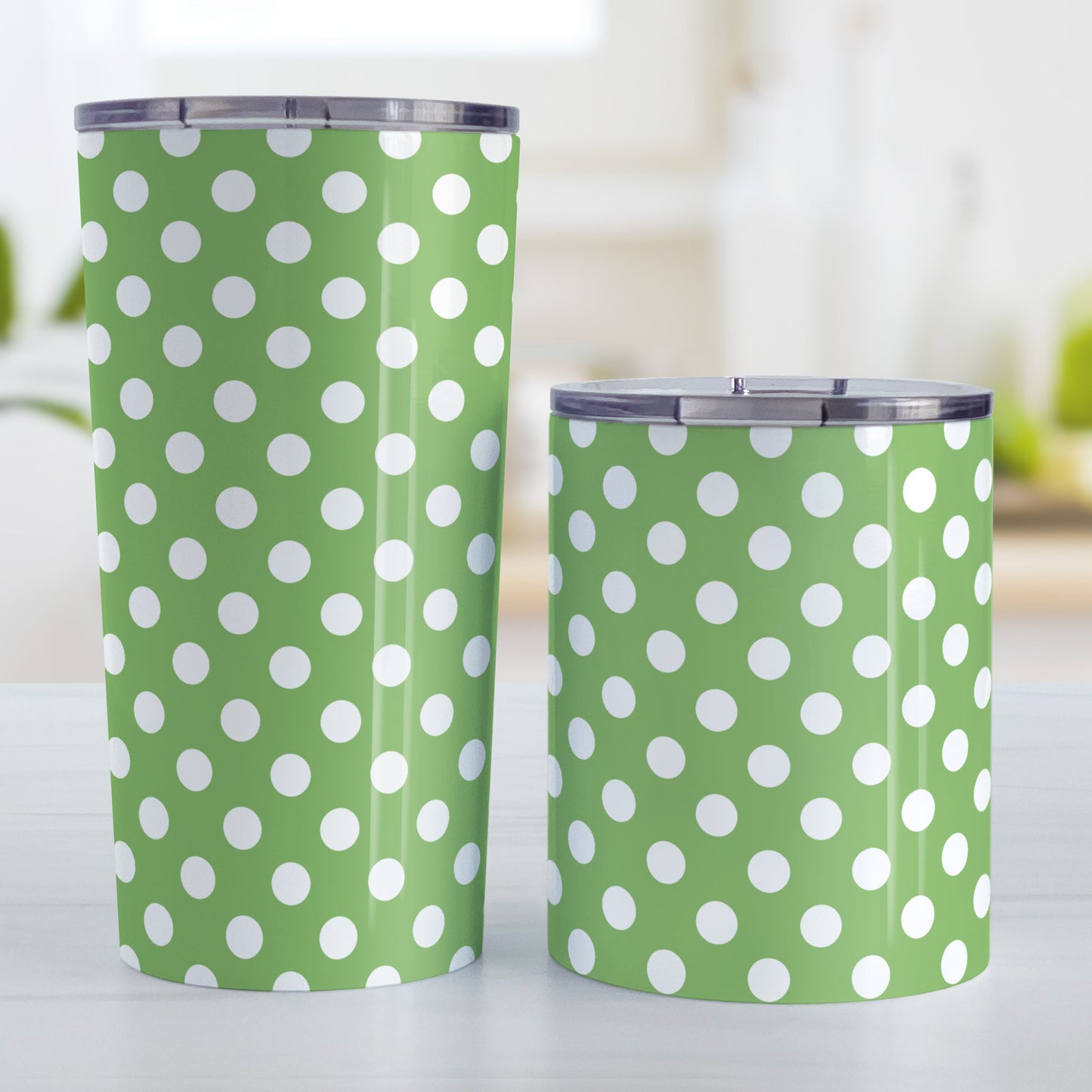 Green Polka Dot Tumbler Cup (20oz and 10oz, stainless steel insulated) at Amy's Coffee Mugs. A tumbler cup designed with a pattern of white polka dots over a green background color that wraps around the cup. Photo shows both sized cups on a table next to each other.