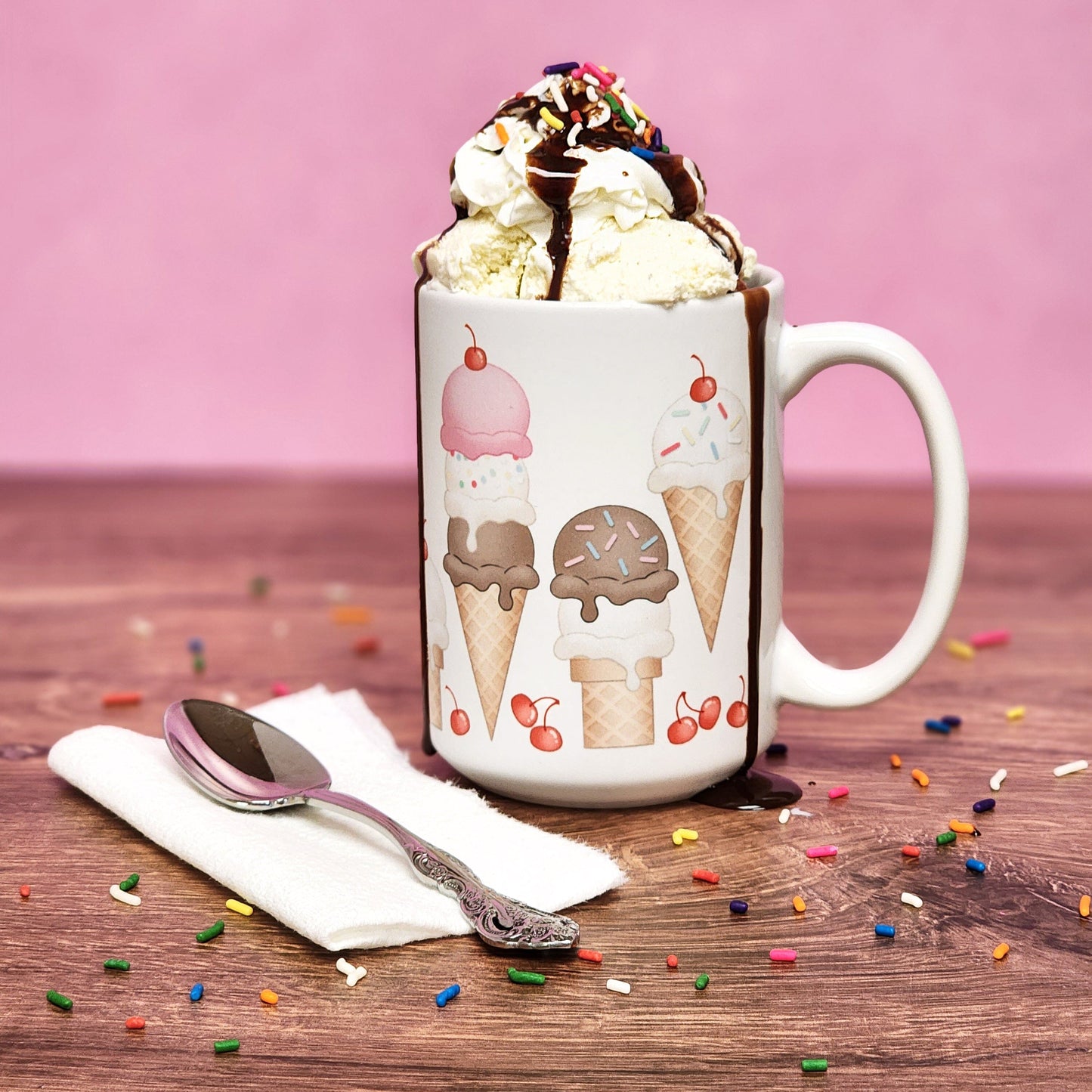 Ice Cream Cones and Cherries Mug (15oz) with ice cream in it, on a walnut wood tabletop and a pink background color.