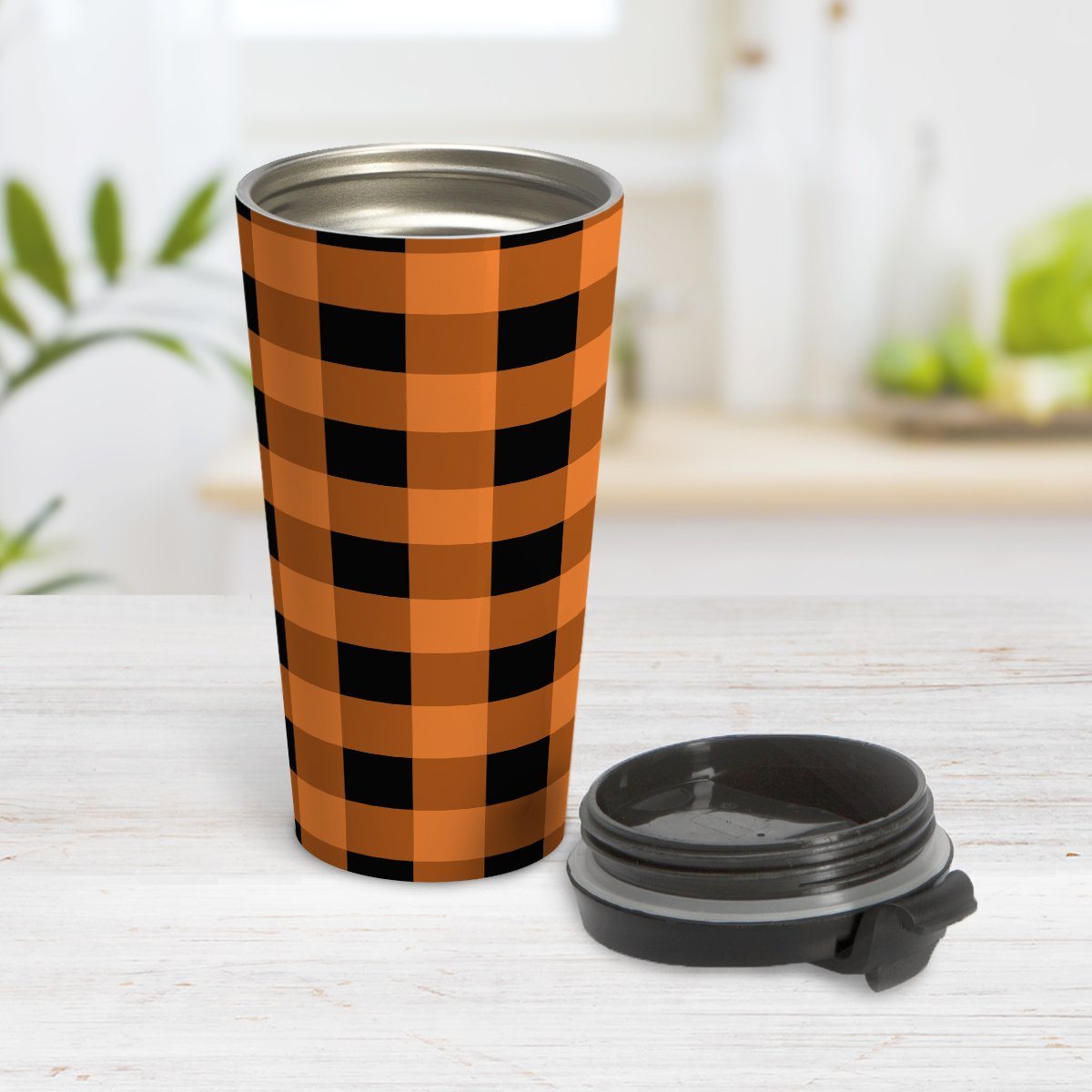 Orange and Black Buffalo Plaid Travel Mug at Amy's Coffee Mugs. A travel mug designed with a black and orange buffalo plaid (buffalo check) pattern that wraps around the mug. Photo shows the mug open on a table with its lid beside it.