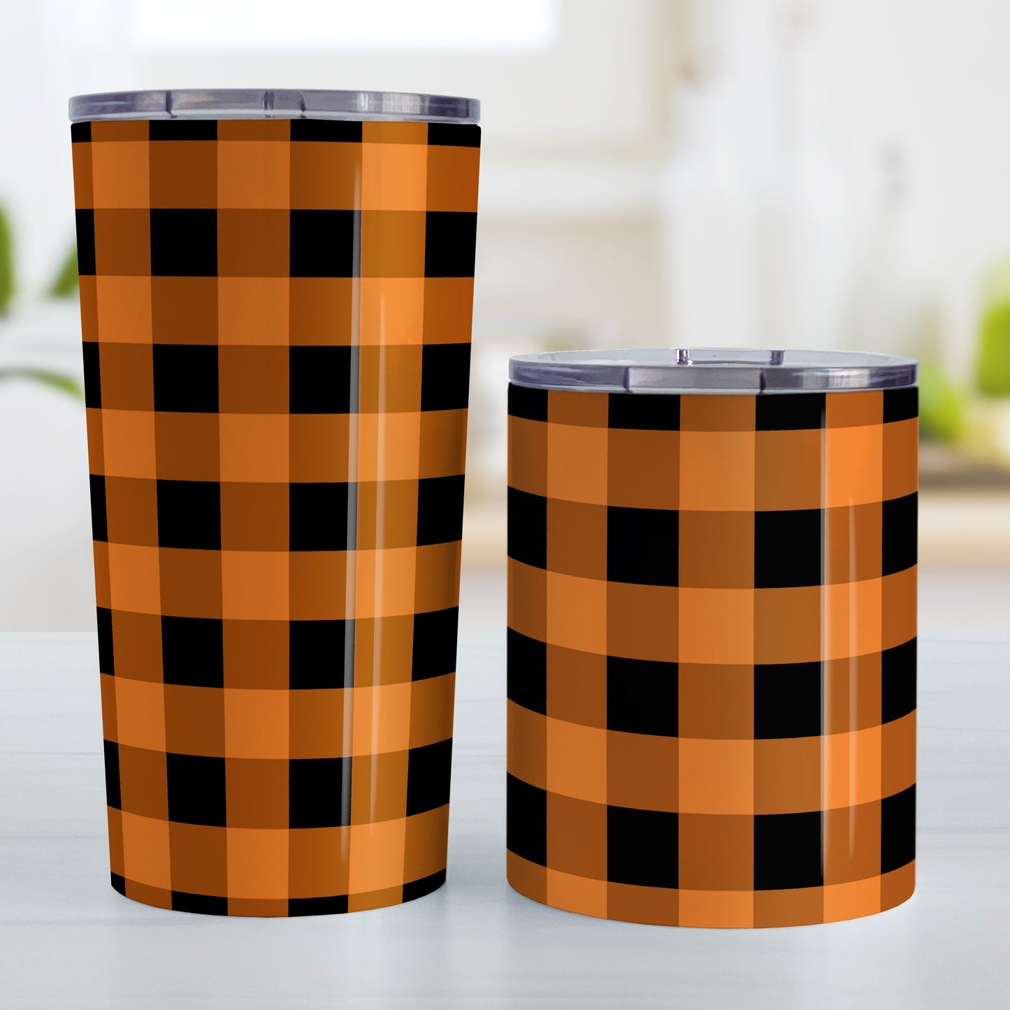 Orange and Black Buffalo Plaid Tumbler Cup (20oz and 10oz, stainless steel insulated) at Amy's Coffee Mugs.A tumbler cup designed with a black and orange buffalo plaid (buffalo check) pattern that wraps around the cup. Photo shows both sized cups on a table next to each other.
