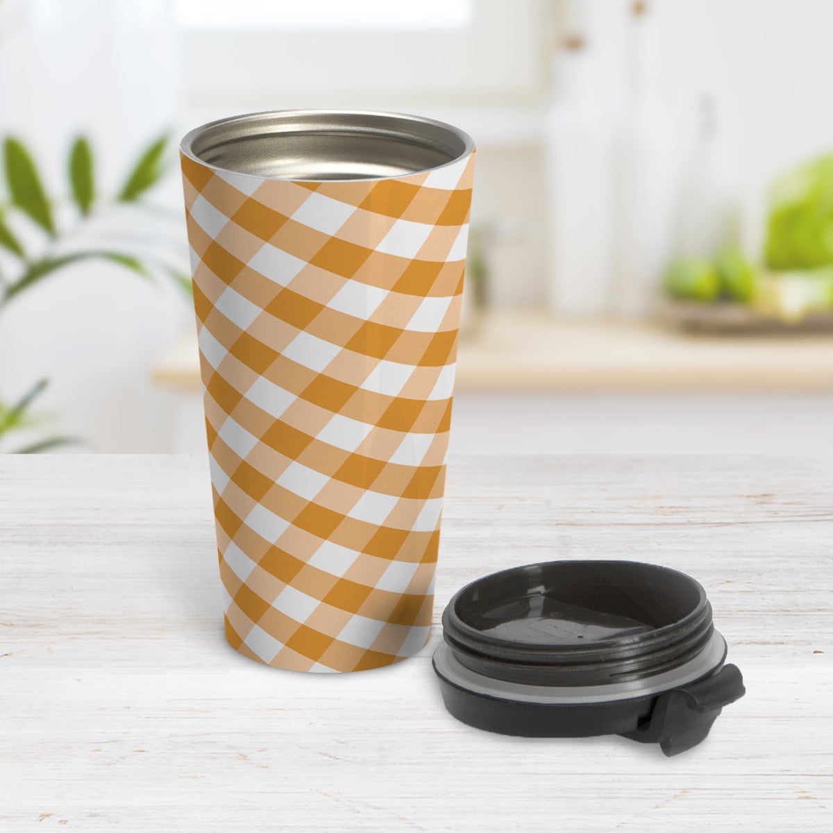 Orange Gingham Travel Mug (15oz) at Amy's Coffee Mugs. A travel mug designed with a slanted orange and white gingham pattern that wraps around the travel mug. Photo shows the mug open on a table with its lid beside it.