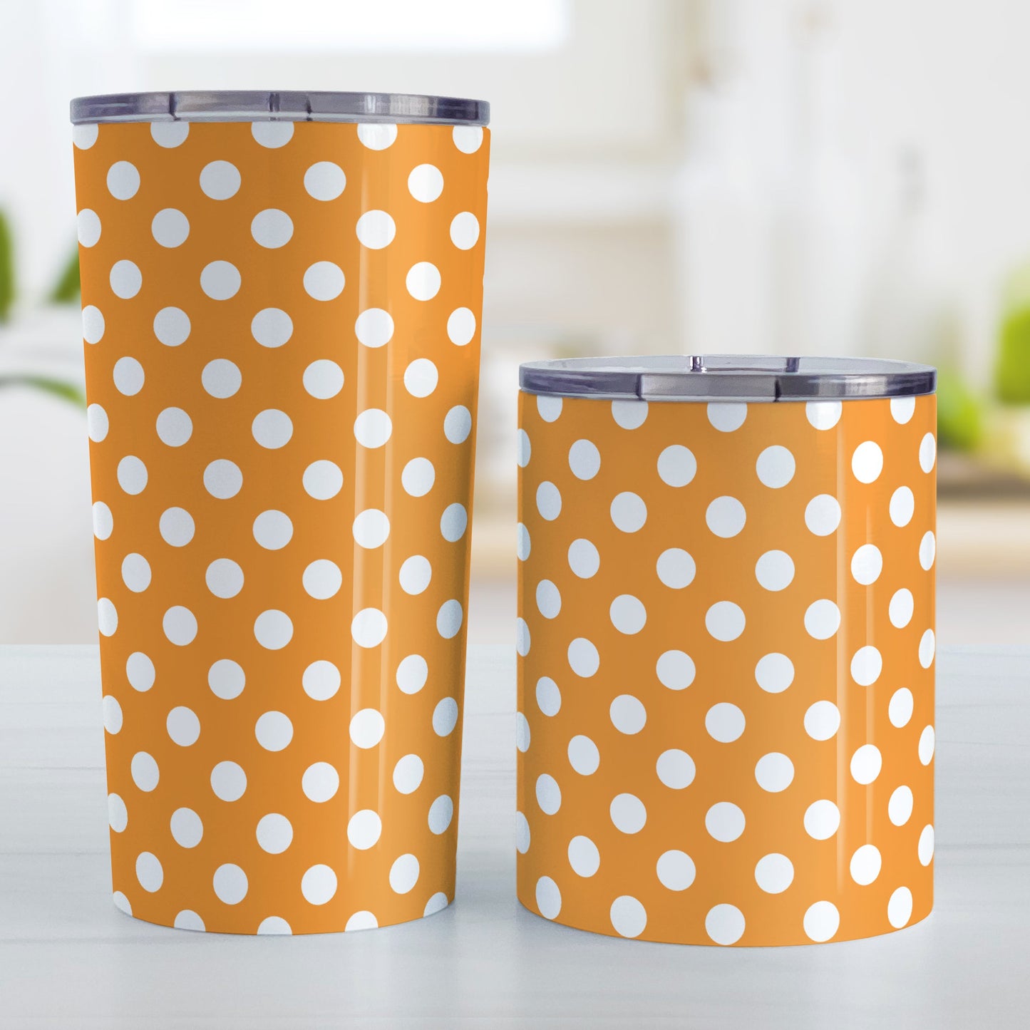 Orange Polka Dot Tumbler Cup (20oz and 10oz, stainless steel insulated) at Amy's Coffee Mugs. A tumbler cup designed with a pattern of white polka dots over an orange background color that wraps around the cup. Photo shows both sized cups on a table next to each other.