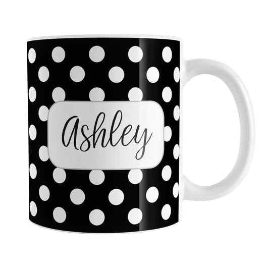 Personalized Black Polka Dot Mug (11oz) at Amy's Coffee Mugs. A ceramic coffee mug designed with a pattern of white polka dots over a black background color that wraps around the mug up to the handle. Your name is personalized in a cute black script font in a white frame design on both sides of the mug over the polka dot pattern.